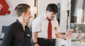 Two men in an office showcasing inclusivity with technology use. One is sitting in a wheelchair.
